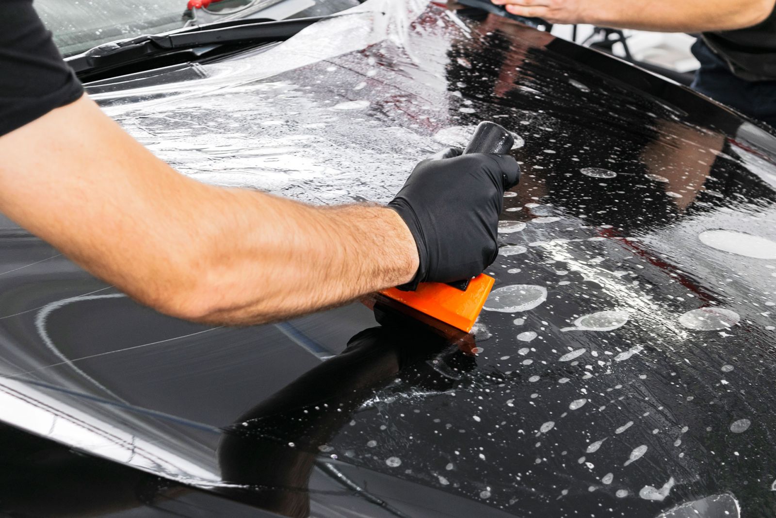 PPF squeegee on gloss black hood